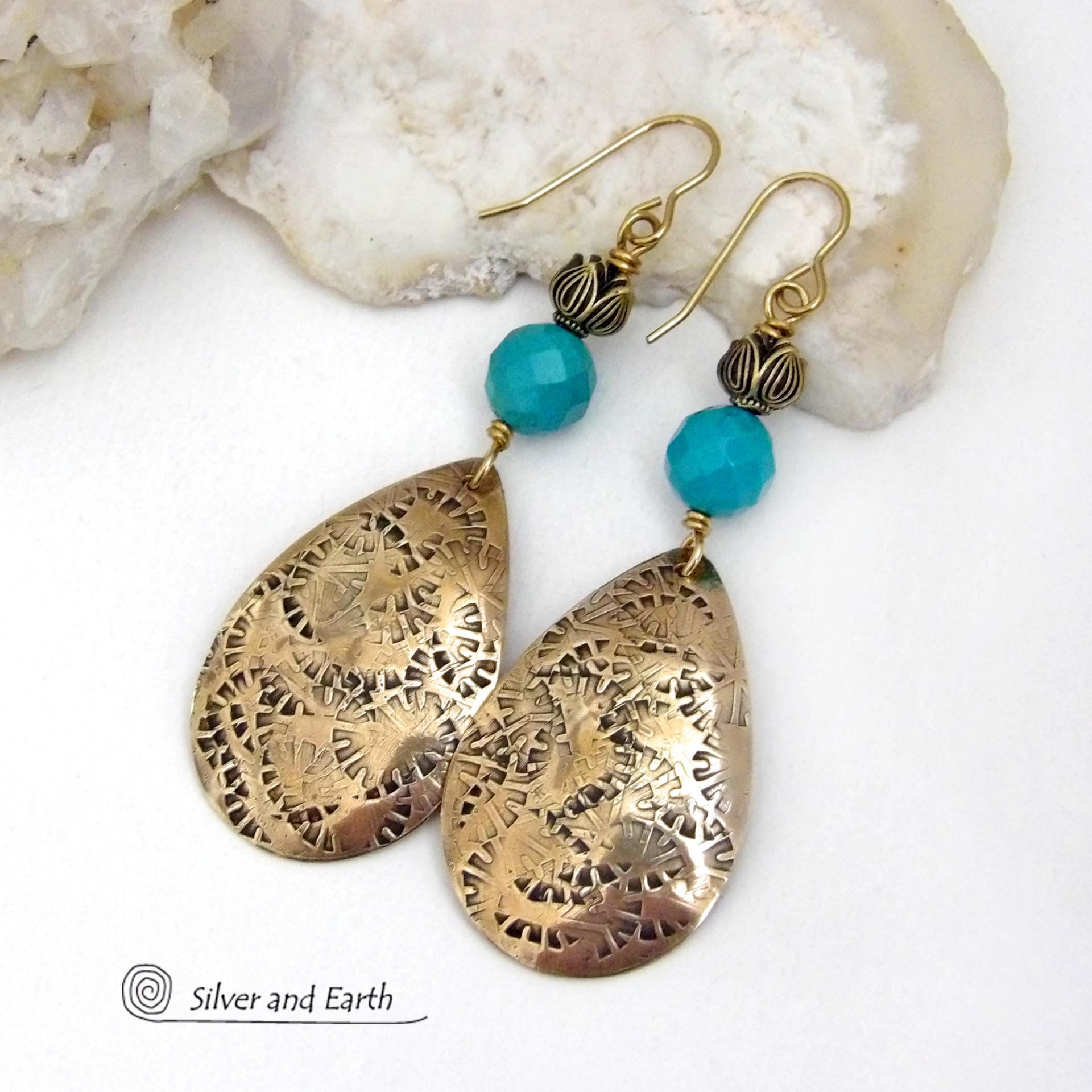 These handcrafted gold brass teardrop dangle earrings have a hand stamped texture accented with natural turquoise gemstones with a faceted finish and tulip flower-shaped brass beads. Big, long and striking - they have a modern elegant boho chic style that makes a bold statement. They'll coordinate beautifully with all wardrobe types - dressed up or down. Handmade in the USA by Silver and Earth Jewelry. 