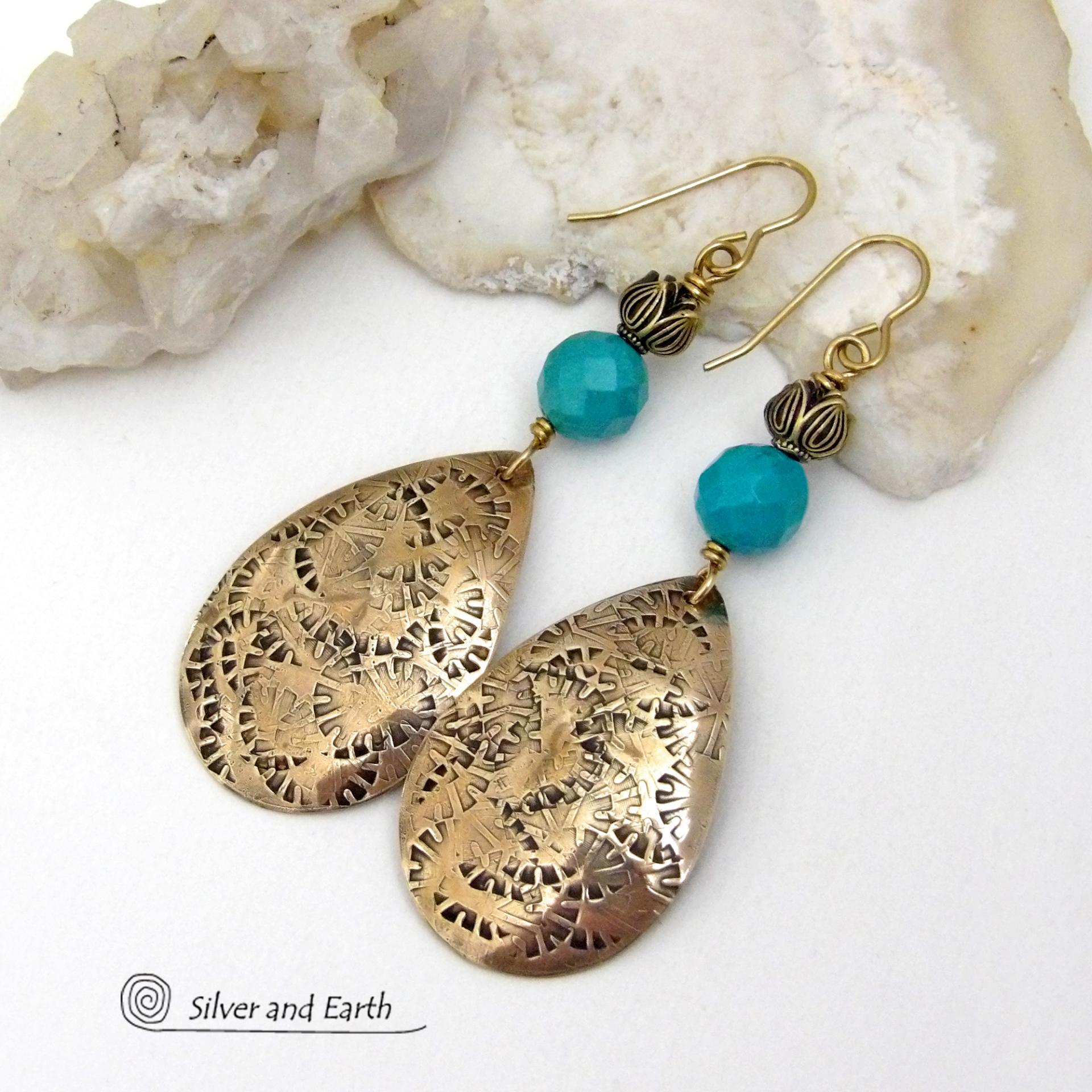 These handcrafted gold brass teardrop dangle earrings have a hand stamped texture accented with natural turquoise gemstones with a faceted finish and tulip flower-shaped brass beads. Big, long and striking - they have a modern elegant boho chic style that makes a bold statement. They'll coordinate beautifully with all wardrobe types - dressed up or down. Handmade in the USA by Silver and Earth Jewelry. 