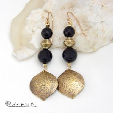 These handcrafted earrings feature gold brass dangles with a hammered raw silk texture accented with black onyx gemstones and brass beads. They have a modern boho chic style with a touch of Egyptian inspired flair that coordinates beautifully with all wardrobe types. Perfect for women that love artisan handcrafted jewelry that makes a bold statement. Handmade in the USA by Silver and Earth Jewelry. 